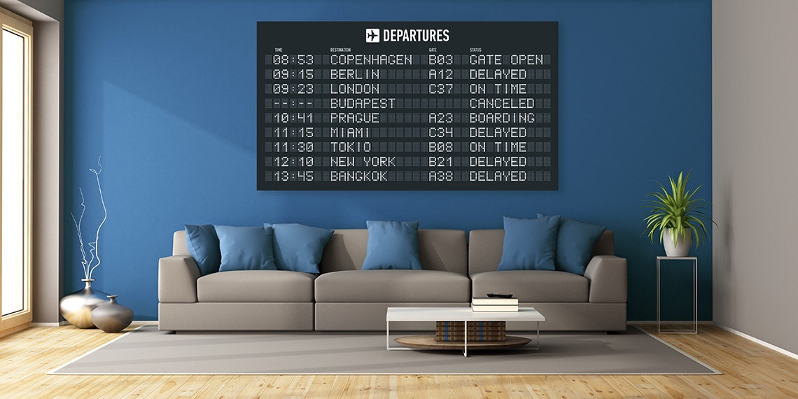 A couch with a chalkboard of departures and destinations behind it.