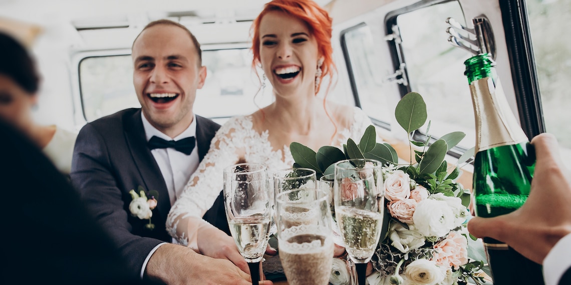 Photo of just-married couple in limo grabbing Champagne flutes.