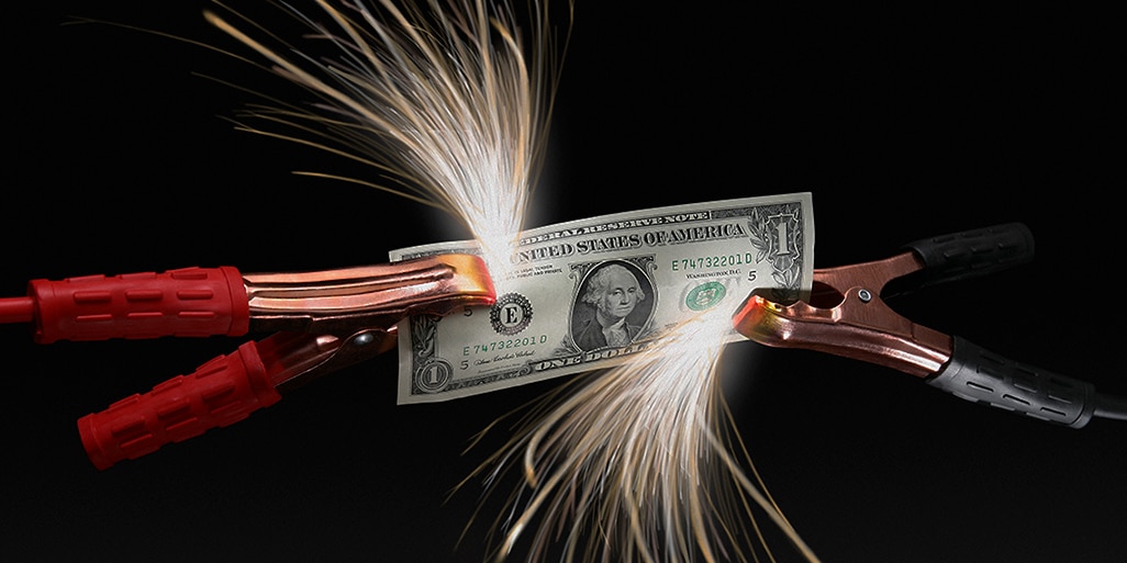 Jumper cables with sparks on a dollar bill.