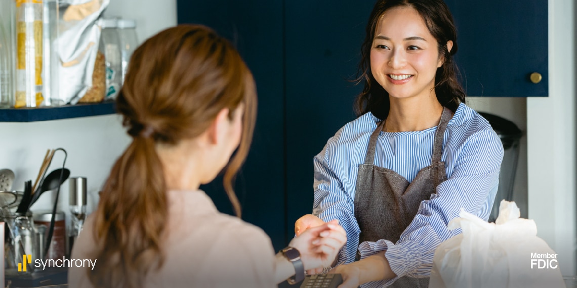 Photo of woman working as a coffee barista helping customer make a purchase.