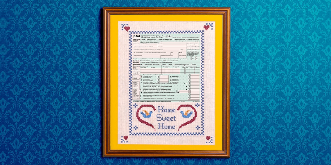 Home Sweet Home needlepoint with a tax form hanging on a wall.