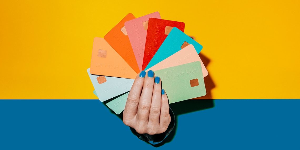 Hand holding a fan of nine colorful credit cards.