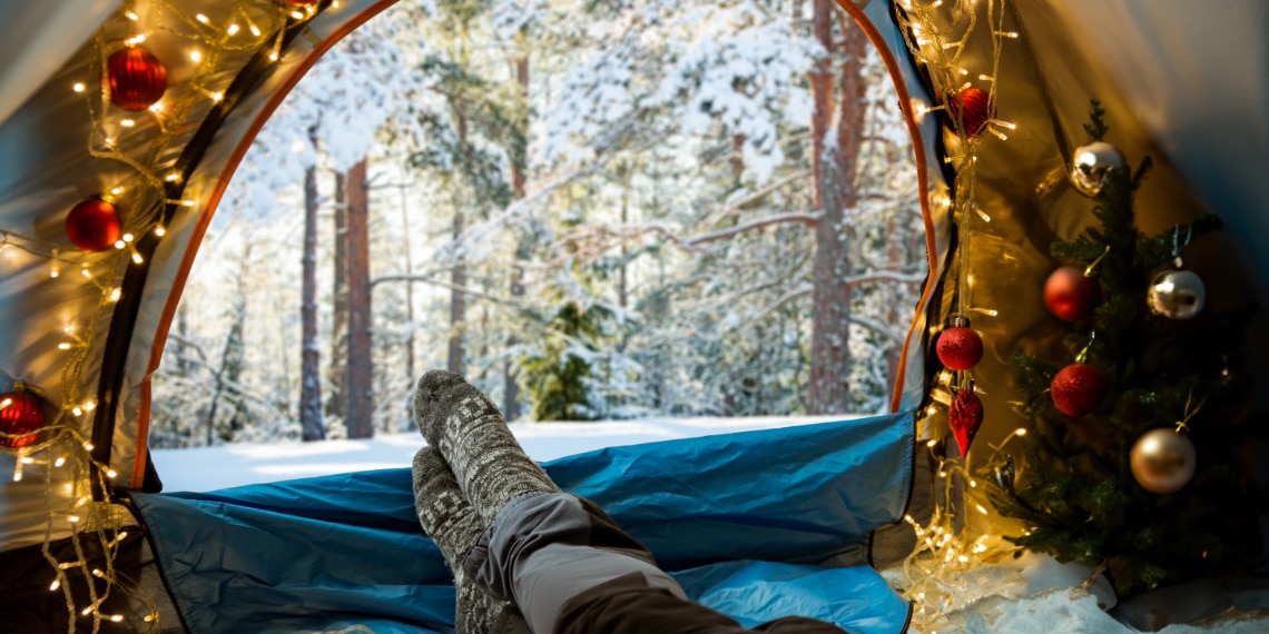 Photo of feet resting inside a holiday decorated camping tent in the winter.