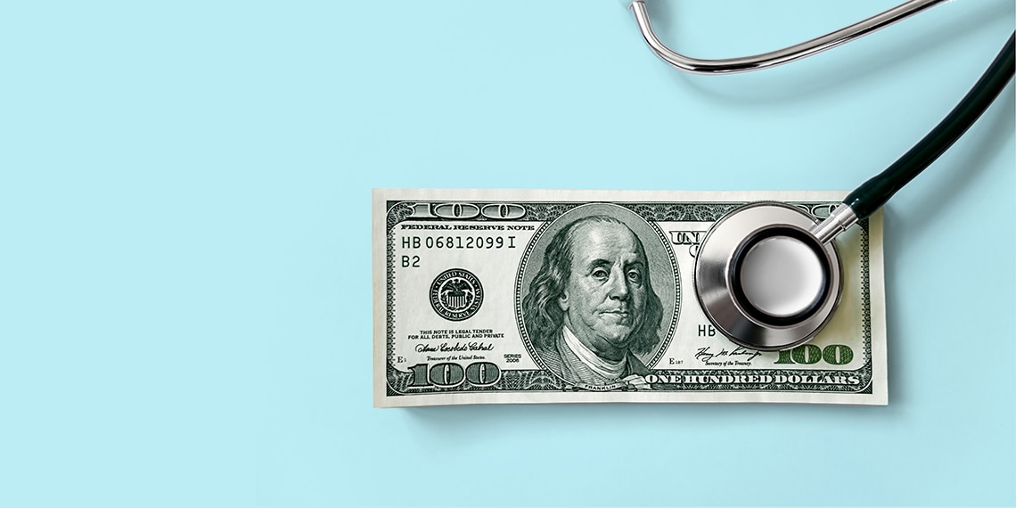 A photo of a hundred dollar bill with a stethoscope resting on it.