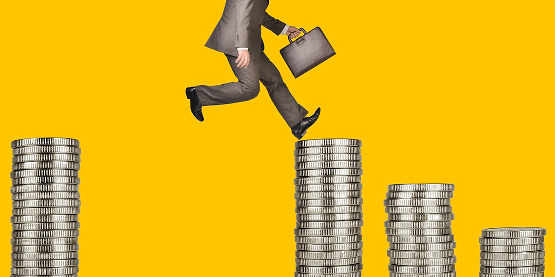 A businessman in a suit climbing over stacks of coins.