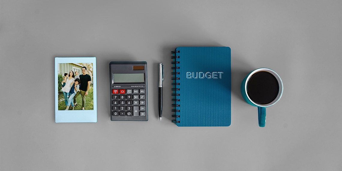 A family photo, calculator, budget book and cup of coffee.